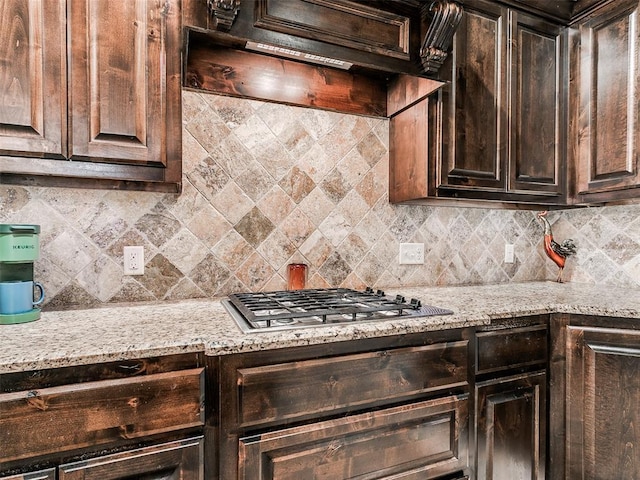 17401 Melville Ln, Edmond, OK 73012 - kitchen featuring decorative backsplash, under cabinet range hood, dark brown cabinets, and light stone counters