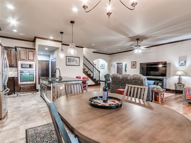 17401 Melville Ln, Edmond, OK 73012 - dining room with arched walkways, crown molding, ceiling fan, stairs, and recessed lighting