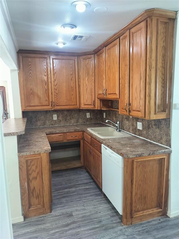 116 SE 39th St, Oklahoma City, OK 73129 - kitchen featuring brown cabinetry, tasteful backsplash, and wood finished floors