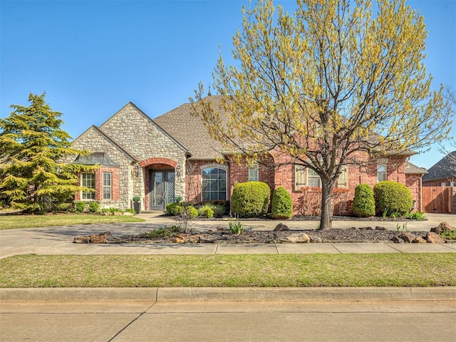 1217 Camelot Dr, Yukon, OK 73099 - french provincial home featuring stone siding, brick siding, and a shingled roof