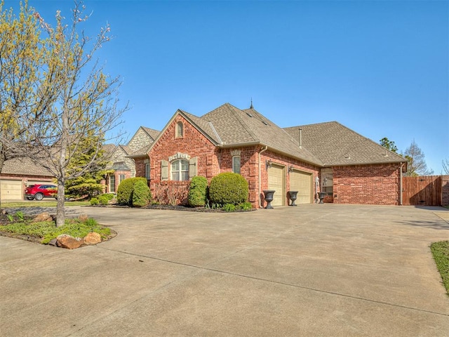 1217 Camelot Dr, Yukon, OK 73099 - french provincial home featuring driveway, a garage, a shingled roof, and brick siding