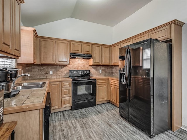 623 SW 37th St, Moore, OK 73160 - kitchen featuring black appliances, vaulted ceiling, light wood-style flooring, decorative backsplash, and under cabinet range hood