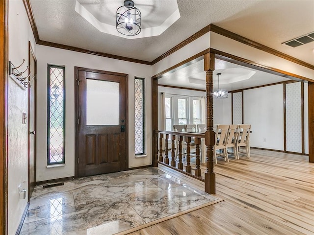 6105 W Gun Hill Way, Warr Acres, OK 73132 - entrance foyer with a chandelier, a tray ceiling, a textured ceiling, wood finished floors, and crown molding