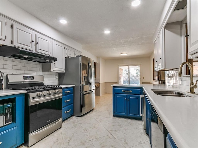 6105 W Gun Hill Way, Warr Acres, OK 73132 - kitchen with blue cabinets, stainless steel appliances, light countertops, under cabinet range hood, and tasteful backsplash
