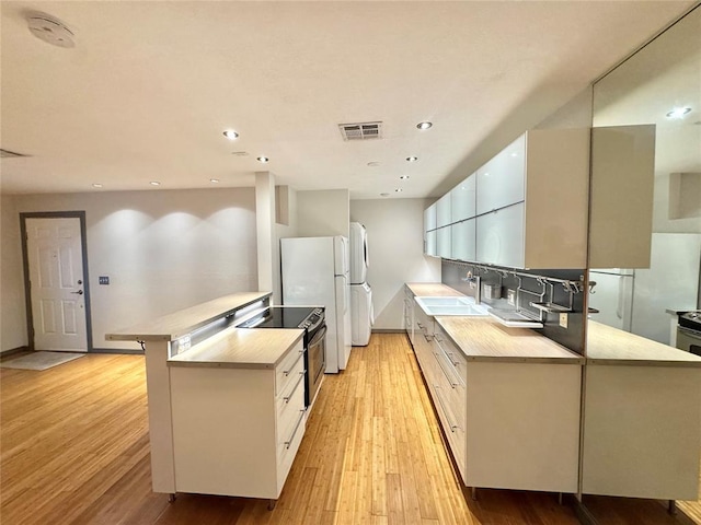 4400 Hemingway Dr Unit 202, Oklahoma City, OK 73118 - kitchen featuring electric range, light wood-style flooring, light countertops, a peninsula, and recessed lighting