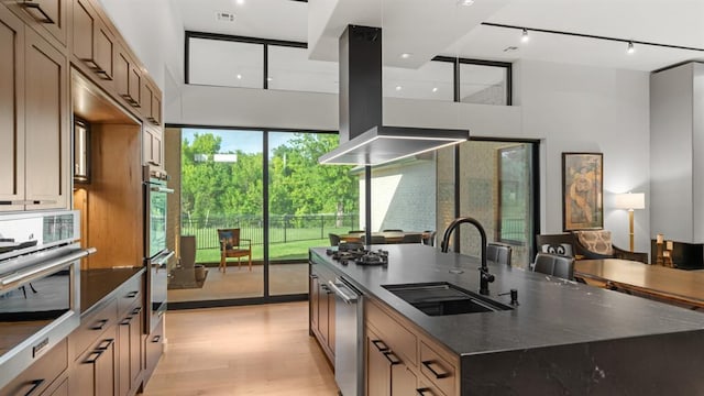 10105 SW 25th Ct, Yukon, OK 73099 - kitchen with a large island with sink, a towering ceiling, light wood-type flooring, range hood, and track lighting