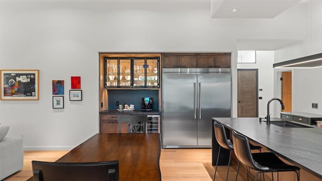 10105 SW 25th Ct, Yukon, OK 73099 - kitchen with stainless steel built in refrigerator, light wood finished floors, a breakfast bar, and dark brown cabinetry