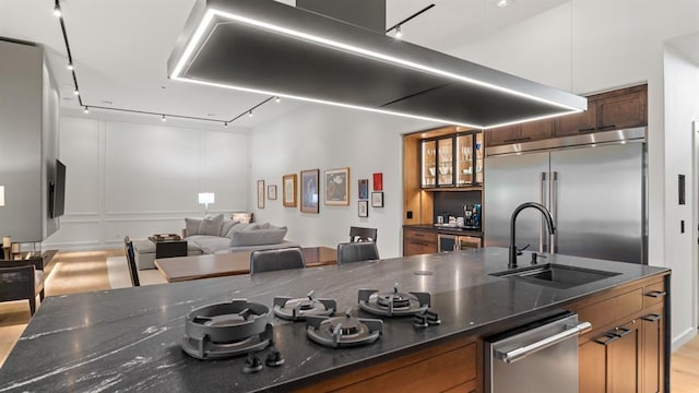 10105 SW 25th Ct, Yukon, OK 73099 - kitchen featuring wall chimney exhaust hood, appliances with stainless steel finishes, open floor plan, rail lighting, and brown cabinetry