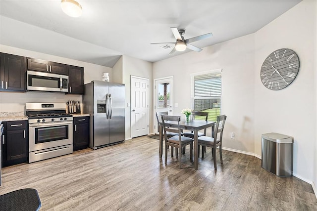 521 Audrey Dr, Tuttle, OK 73089 - kitchen with stainless steel appliances, light wood finished floors, ceiling fan, and dark brown cabinetry