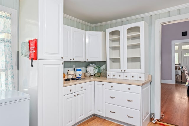 508 Newton Ave, Ozark, AL 36360 - kitchen with light countertops, glass insert cabinets, white cabinets, light wood-style floors, and ornamental molding