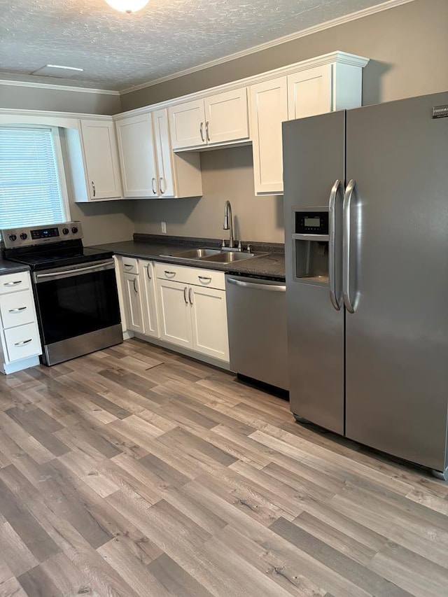 123 Hedstrom Dr, Dothan, AL 36301 - kitchen featuring stainless steel appliances, crown molding, dark countertops, light wood-style flooring, and white cabinetry