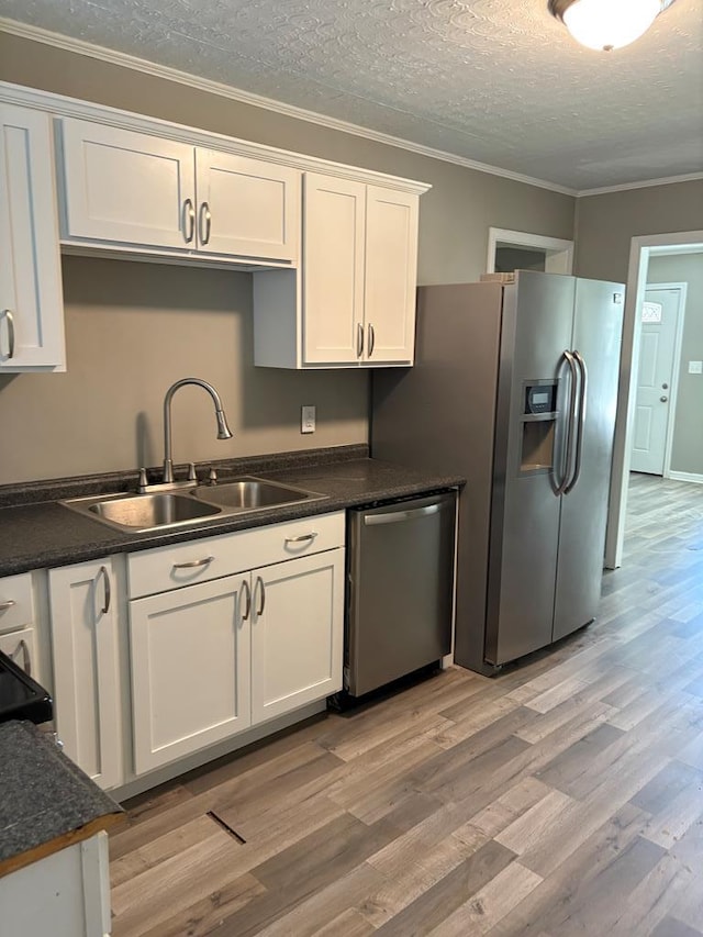 123 Hedstrom Dr, Dothan, AL 36301 - kitchen featuring appliances with stainless steel finishes, white cabinets, light wood-type flooring, dark countertops, and ornamental molding
