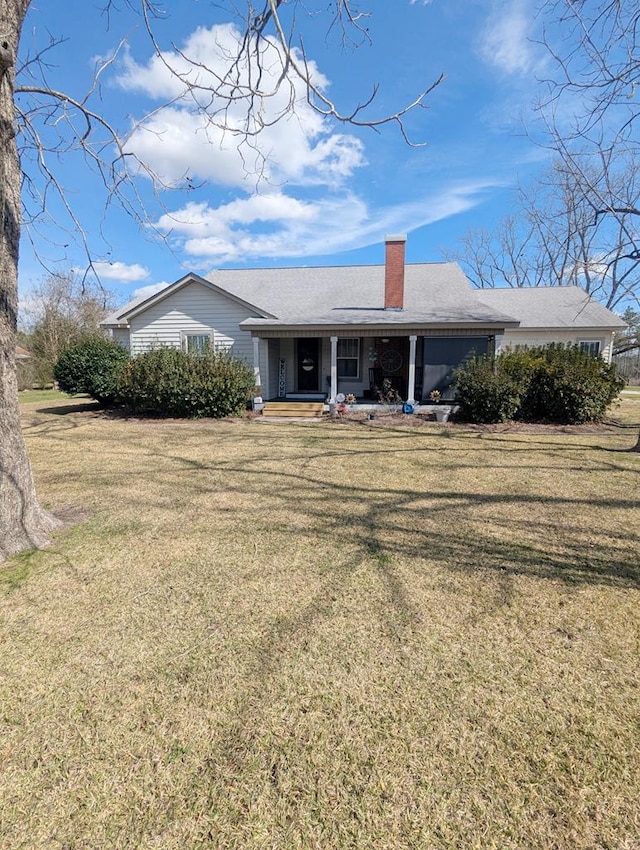 view of front of home with a chimney, a porch, and a front yard