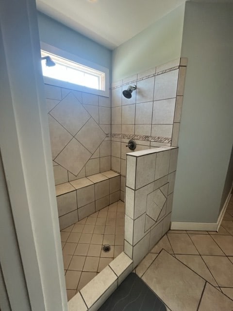 full bath featuring baseboards, a tile shower, and tile patterned floors