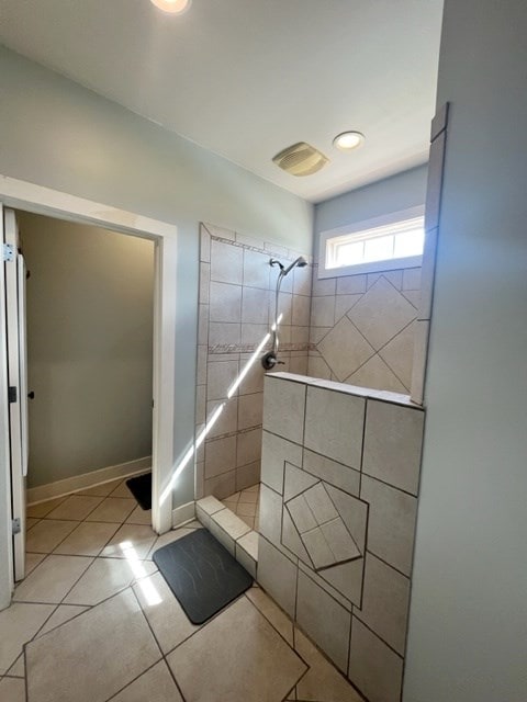 full bathroom with tile patterned flooring, a tile shower, and baseboards