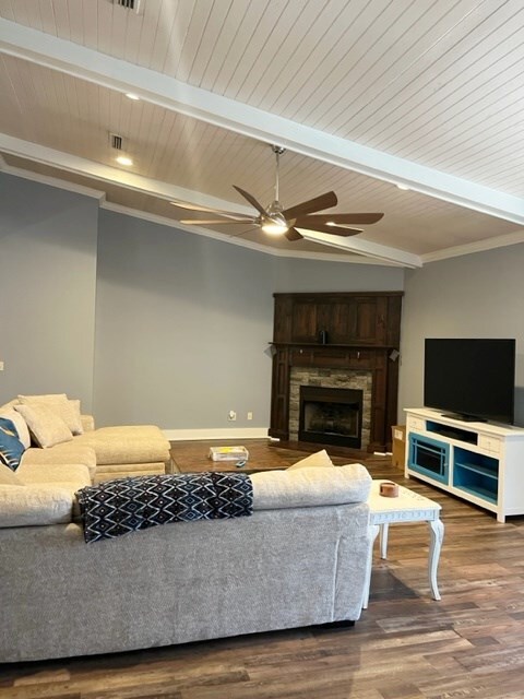 living room featuring a fireplace, lofted ceiling with beams, a ceiling fan, wood finished floors, and baseboards