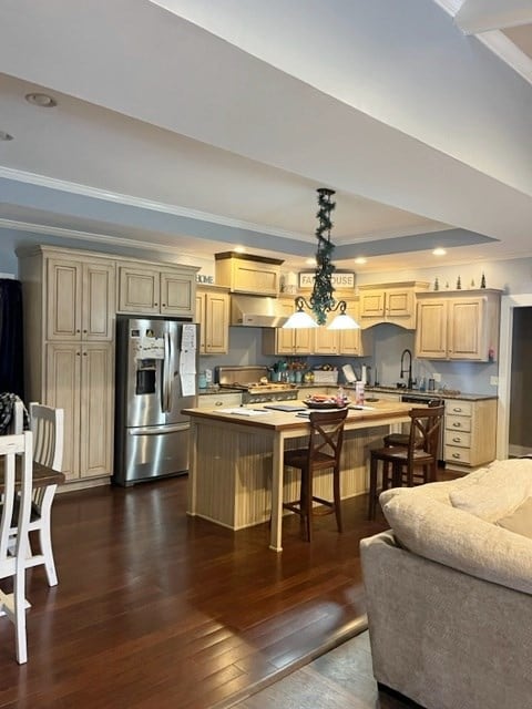 kitchen with under cabinet range hood, a center island, dark wood-style floors, stainless steel fridge, and crown molding