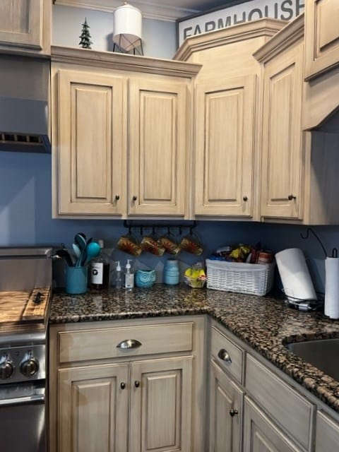 kitchen with ornamental molding, dark stone countertops, and light brown cabinets