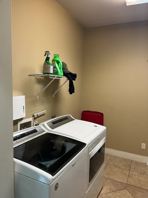 laundry area with light tile patterned floors, laundry area, washer and clothes dryer, and baseboards