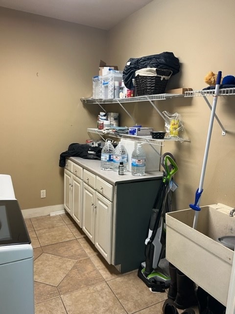 laundry area with cabinet space, baseboards, and light tile patterned floors