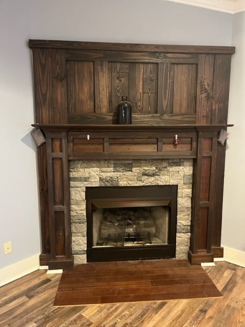 room details with a stone fireplace, wood finished floors, and baseboards