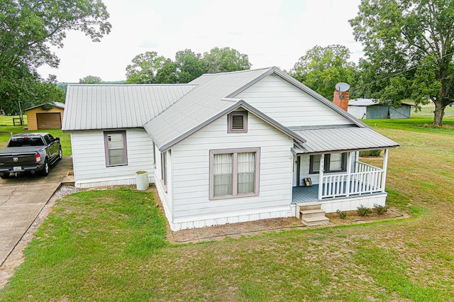 bungalow featuring a porch, a front yard, metal roof, and driveway