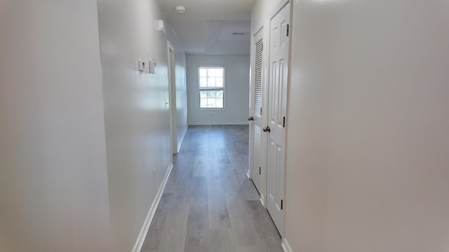 hall with light wood-style floors and baseboards