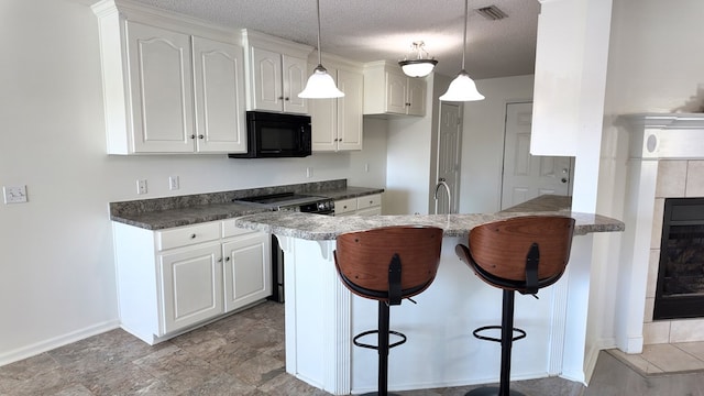kitchen with a breakfast bar, black microwave, visible vents, and electric stove