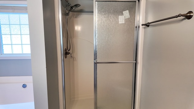 full bathroom featuring a stall shower, a wealth of natural light, and a bathtub