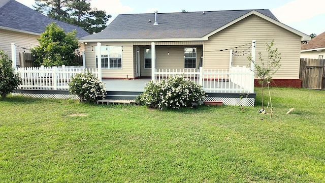 back of house with a yard, a deck, a shingled roof, and fence