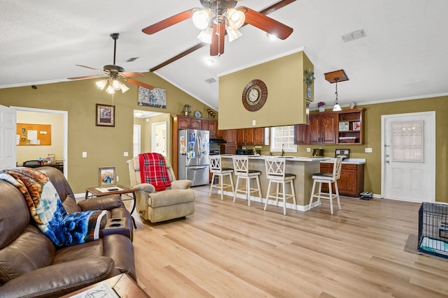 living area with vaulted ceiling, light wood-type flooring, visible vents, and baseboards