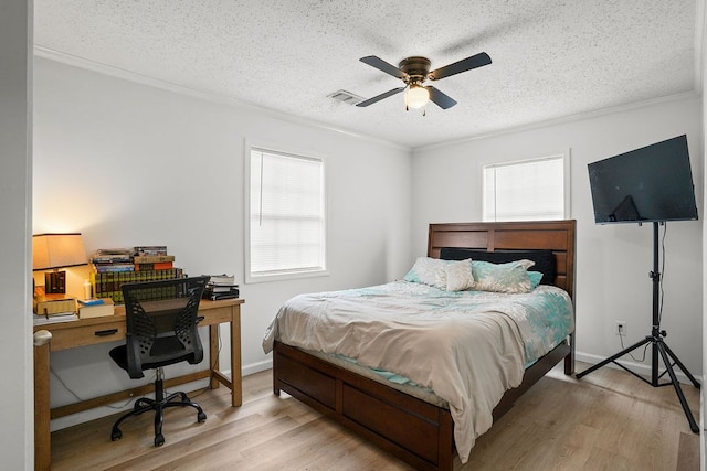 bedroom featuring light wood-style floors, multiple windows, visible vents, and a textured ceiling