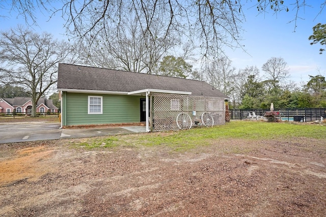 rear view of property with a shingled roof, fence, and a lawn