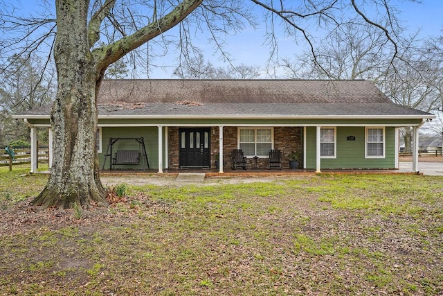 view of front of home with a shingled roof, a front yard, and covered porch