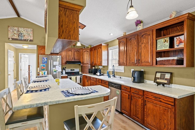 kitchen with appliances with stainless steel finishes, a kitchen breakfast bar, light countertops, pendant lighting, and a sink