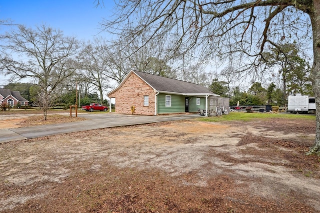 view of property exterior featuring driveway, brick siding, and fence