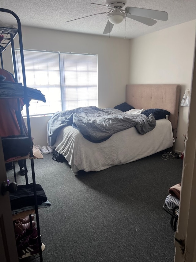 carpeted bedroom featuring ceiling fan and a textured ceiling