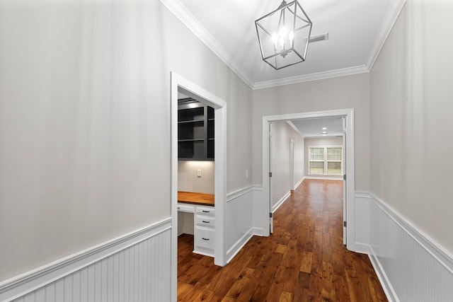 hallway featuring dark wood-type flooring, a notable chandelier, and ornamental molding