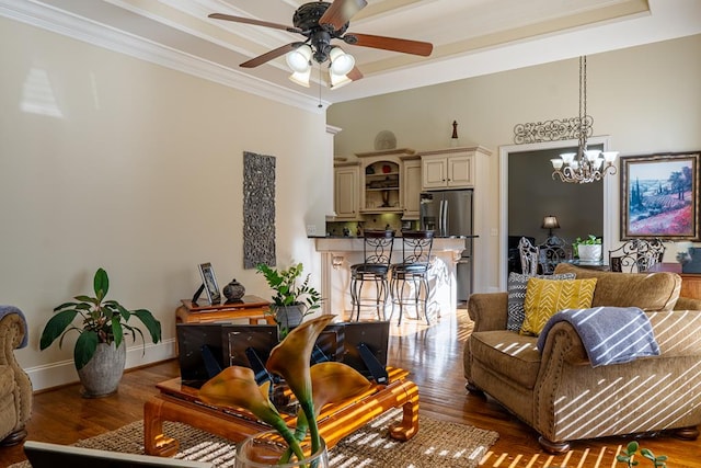 living room with ceiling fan with notable chandelier, dark hardwood / wood-style flooring, a tray ceiling, and ornamental molding