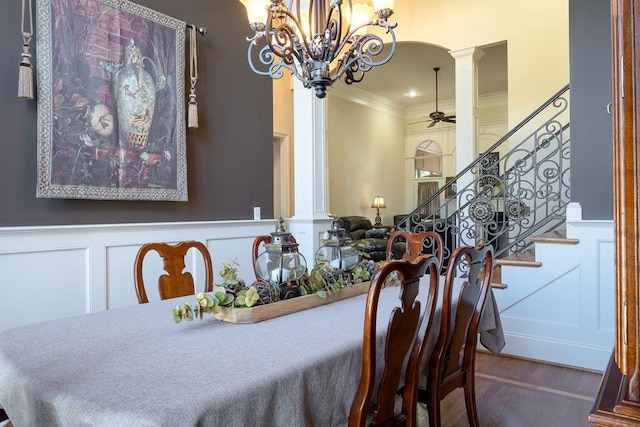 dining room featuring wood-type flooring, ceiling fan with notable chandelier, decorative columns, and crown molding