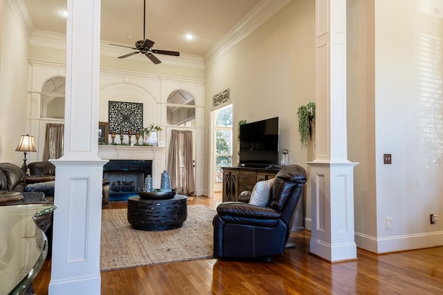 living room with hardwood / wood-style flooring, ceiling fan, ornate columns, and crown molding