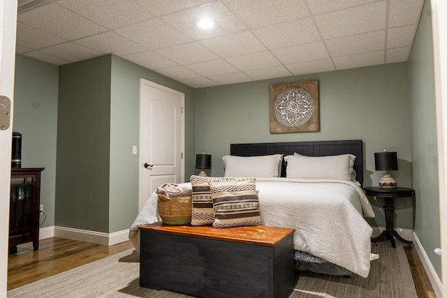 bedroom with a paneled ceiling and hardwood / wood-style floors