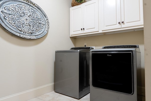 laundry area featuring cabinets, light tile patterned floors, and washing machine and clothes dryer