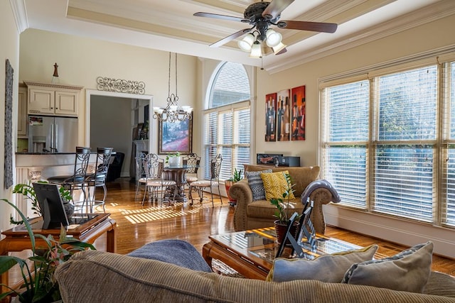 living room featuring ceiling fan with notable chandelier, a healthy amount of sunlight, ornamental molding, and light hardwood / wood-style flooring