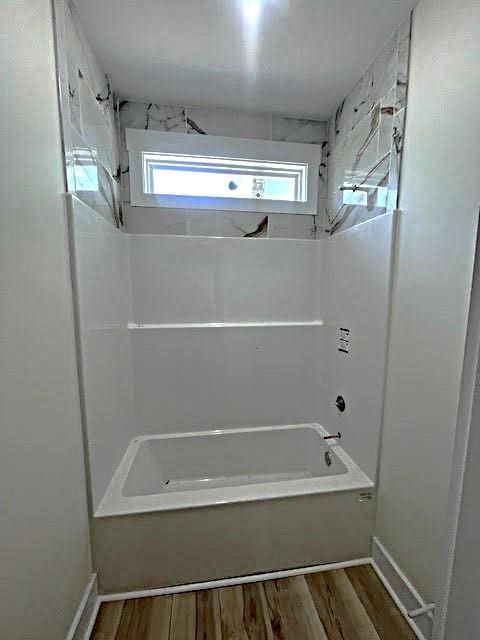 full bath featuring wood finished floors, baseboards, and bathing tub / shower combination
