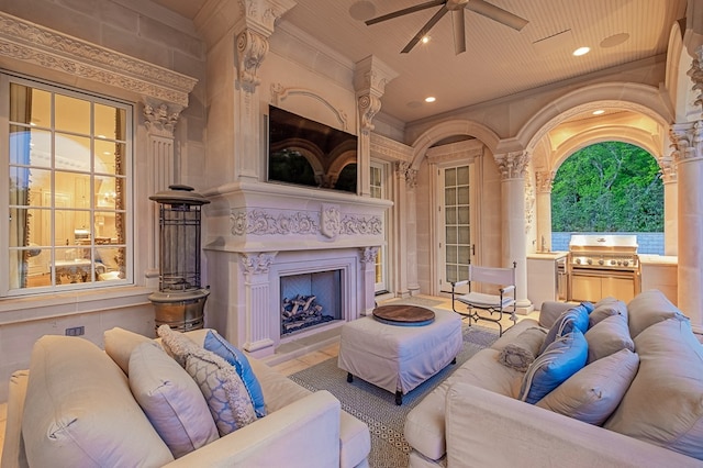 living room with exterior fireplace, ornamental molding, and ceiling fan