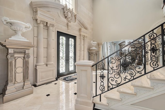 entrance foyer featuring a high ceiling, decorative columns, and french doors