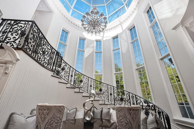 staircase with a towering ceiling and a notable chandelier