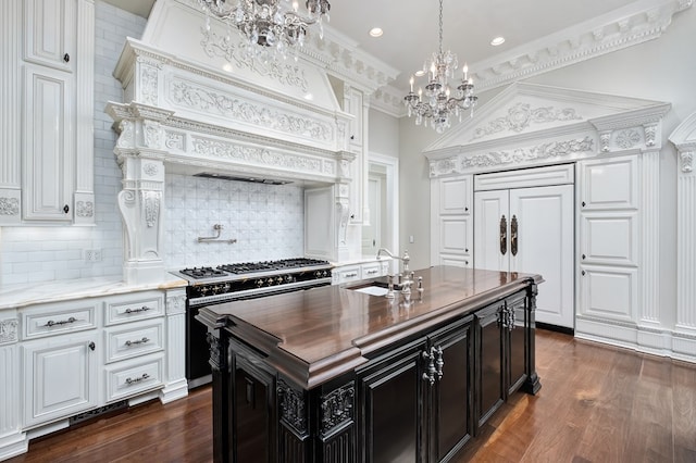 kitchen featuring double oven range, a kitchen island with sink, dark wood-type flooring, sink, and ornamental molding