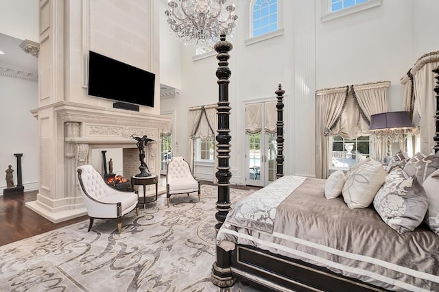 bedroom featuring a towering ceiling, access to outside, crown molding, a chandelier, and hardwood / wood-style floors